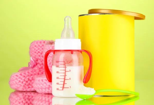 Bottle with milk and food for babies on green background — Stock Photo, Image