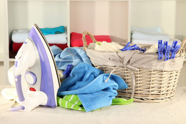 Одежда и утюг на столе на полках
