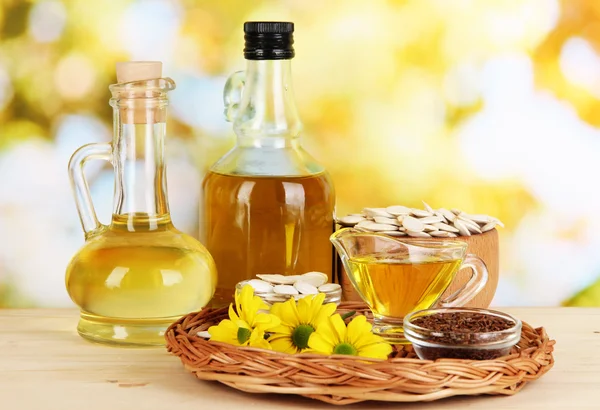 Useful linseed oil and pumpkin seed oil on wooden table on natural background — Stock Photo, Image