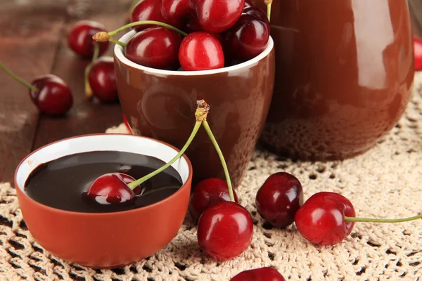 Bayas rojas maduras de cereza en taza y salsa de chocolate en primer plano de mesa de madera —  Fotos de Stock