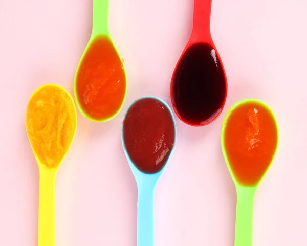 Baby puree in spoons on pink background — Stock Photo, Image