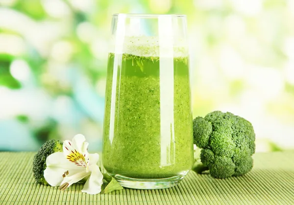 Bicchiere di succo di broccolo, su tappetino di bambù, su fondo verde — Foto Stock