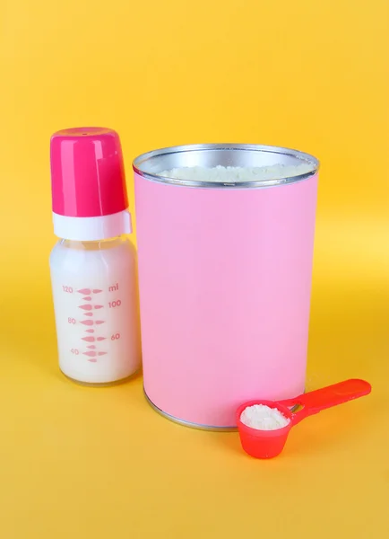 Mjölkpulver med nappflaska mjölk på gul bakgrund — Stockfoto