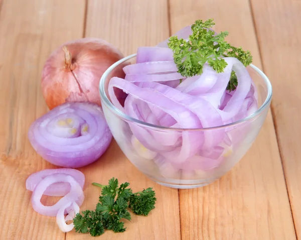 Onion cut with rings in bowl on wooden table close-up — Stock Photo, Image