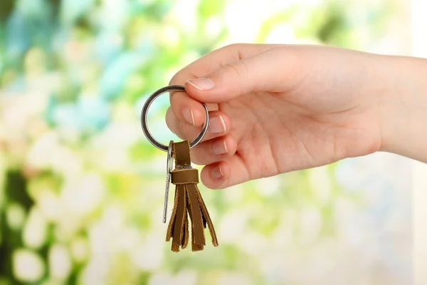 Nyckel med läder prydnadssak i handen på ljus bakgrund — Stockfoto