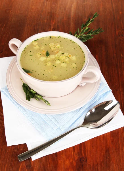 Nährende Suppe in rosa Pfanne auf Holztisch in Großaufnahme — Stockfoto