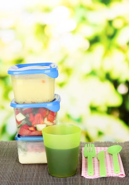 Tasty lunch in plastic containers, on bamboo mat on bright background — Stock Photo, Image