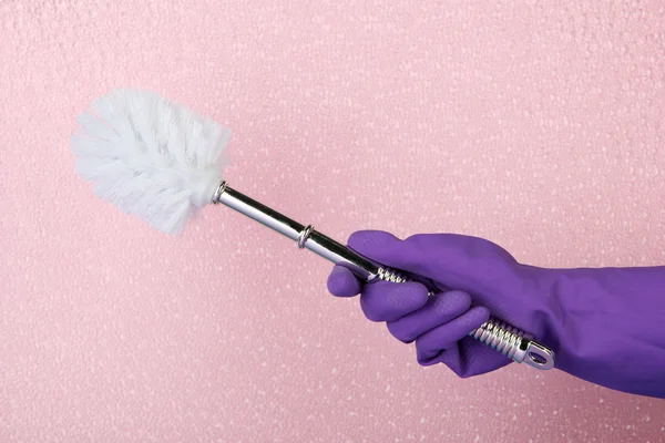 Toilet brush in hand on pink background — Stock Photo, Image