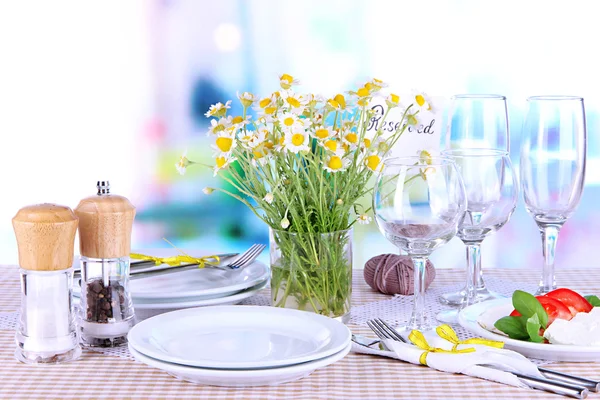 Table setting with chamomiles on checkered tablecloth on window background — Stock Photo, Image