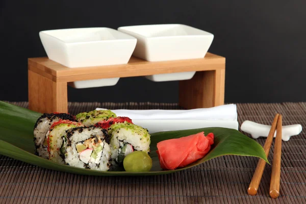 Pyszne maki sushi - rolki na zielony liść na stole na szarym tle — Zdjęcie stockowe