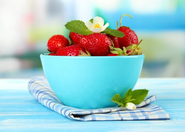 Ripe sweet strawberries in bowl on blue wooden table — Stock Photo, Image