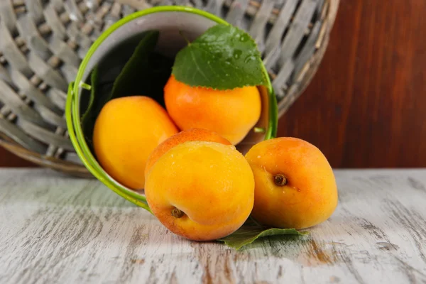 Apricots in bucket on wooden table near wicker coasters — Stock Photo, Image