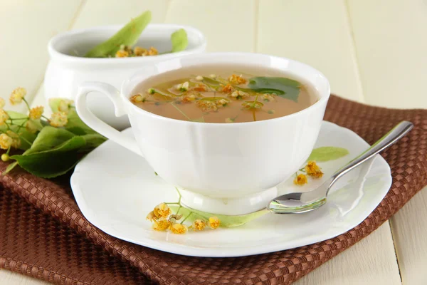 Cup of tea with linden on napkin on wooden table — Stock Photo, Image