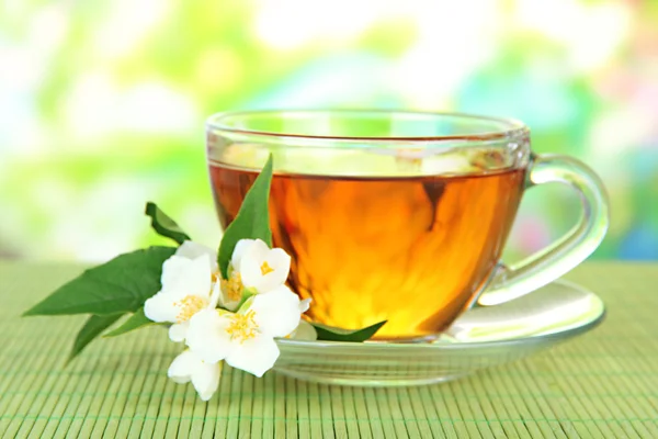 Taza de té con jazmín, sobre estera de bambú, sobre fondo brillante —  Fotos de Stock