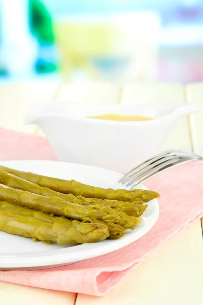 Asperges op plaat, op houten tafel op lichte achtergrond — Stockfoto