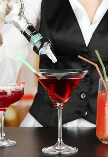 Barmen hand with shaker pouring cocktail into glass, on bright background — Stock Photo, Image