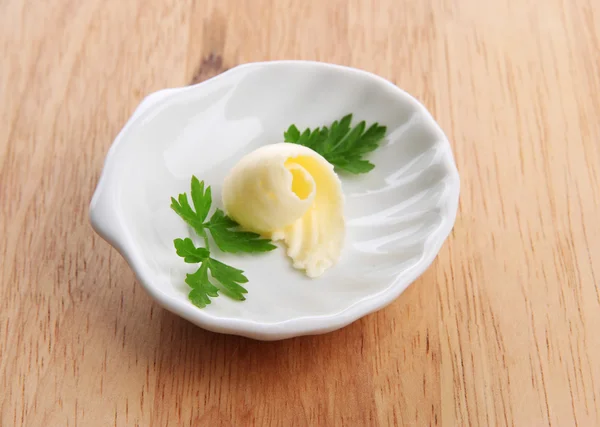 Boucle de beurre sur assiette, sur table en bois — Photo