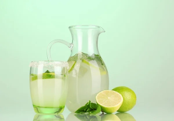 Lemonade in pitcher and glass on turquoise background — Stock Photo, Image