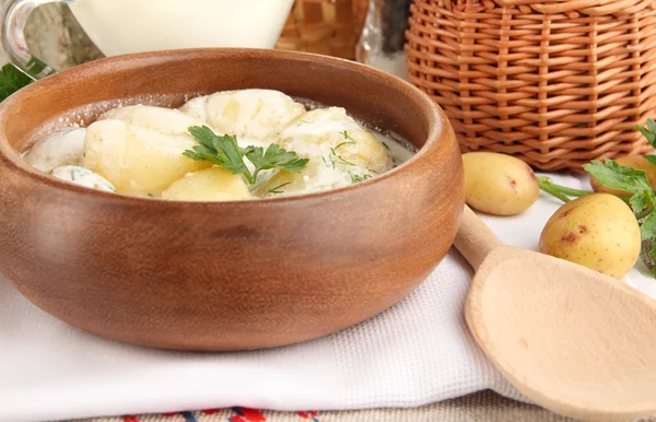 Tender young potatoes with sour cream and herbs in wooden bowl on tablecloth close-up — Stock Photo, Image