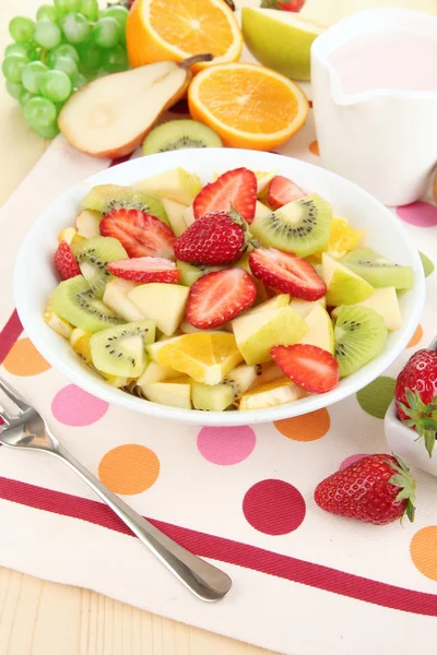 Useful fruit salad of fresh fruits and berries in bowl on napkin on wooden table close-up — Stock Photo, Image