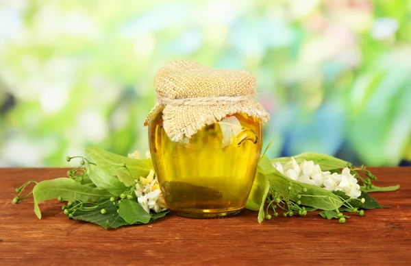 Jar of honey with flowers of lime, acacia on wooden table, on bright background — Stock Photo, Image