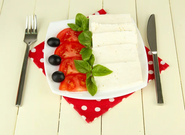 Sheep milk cheese, with basil and tomato on color napkin on wooden background — Stock Photo, Image