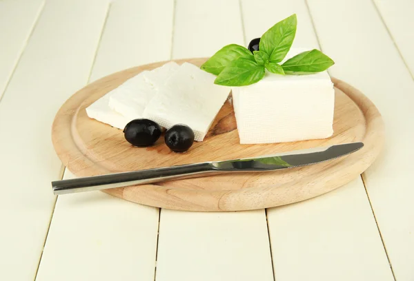 Brânză din lapte de oaie, măsline negre, cu busuioc pe placa de tăiere, izolată pe alb — Fotografie, imagine de stoc