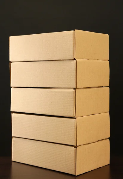 Коробки для посылок на деревянном столе, на черном фоне — стоковое фото