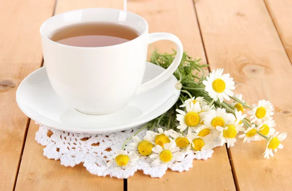 Cup of chamomile tea and chamomile on wooden table — Stock Photo, Image