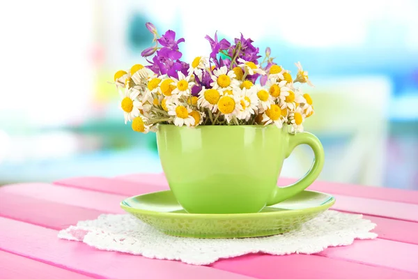 Bouquet of chamomile flowers in cup, on bright background — Stock Photo, Image