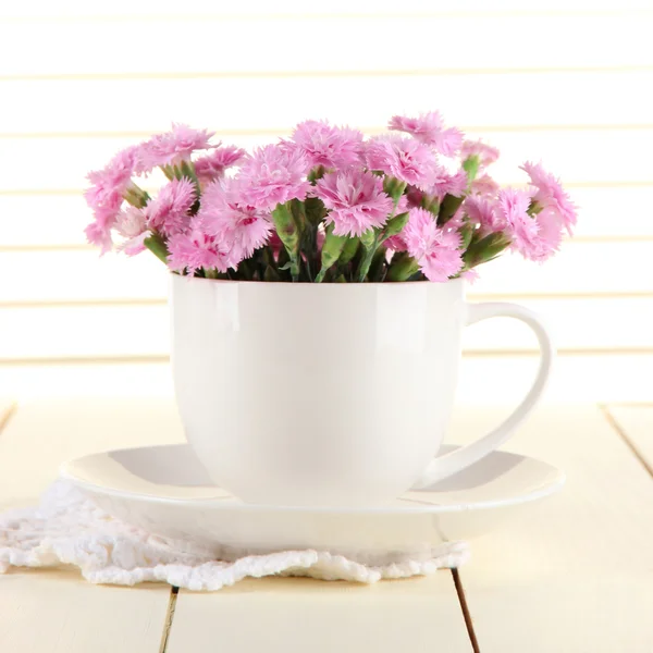 Muchos pequeños dientes de color rosa en taza sobre fondo de madera — Foto de Stock