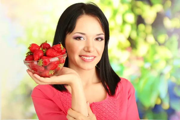 Hermosa joven con fresas sobre fondo natural — Foto de Stock