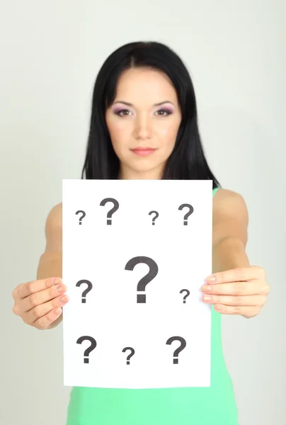 Woman with question marks on grey background — Stock Photo, Image