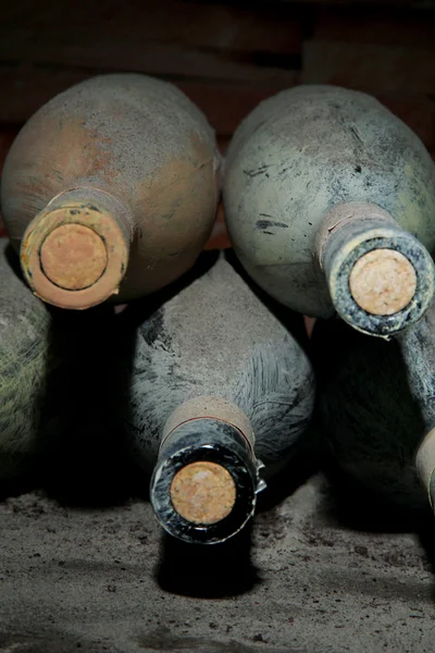 Old bottles of wine in old cellar, on dark background — Stock Photo, Image