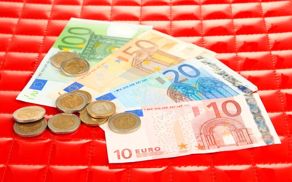 Euro banknotes and euro cents on red background — Stock Photo, Image