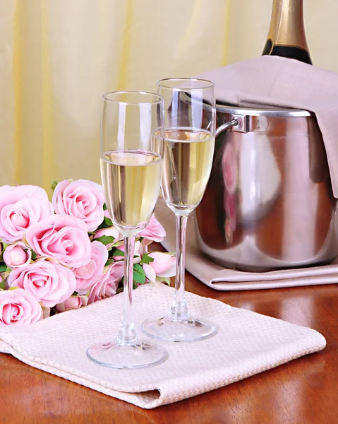 Шампанское и бокалы на круглом столе на фоне ткани — стоковое фото