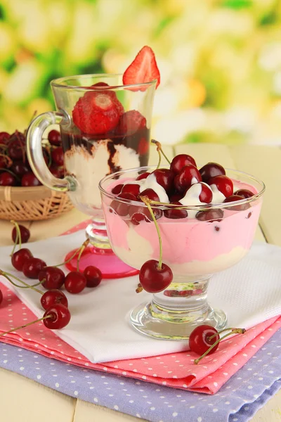 Deliziosi dessert alla fragola e ciliegia in vaso di vetro su tavolo di legno su sfondo naturale — Foto Stock