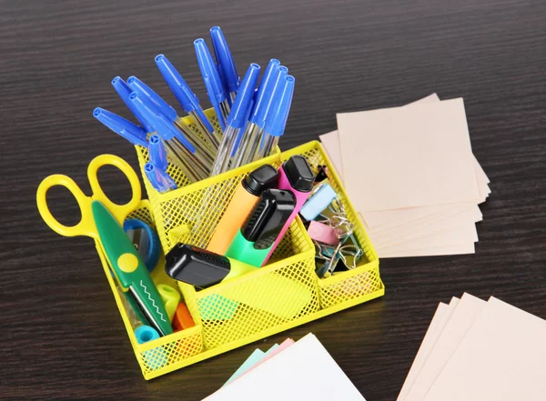 Kantoorapparatuur in gele stationaire houder op donkere houten tafel — Stockfoto