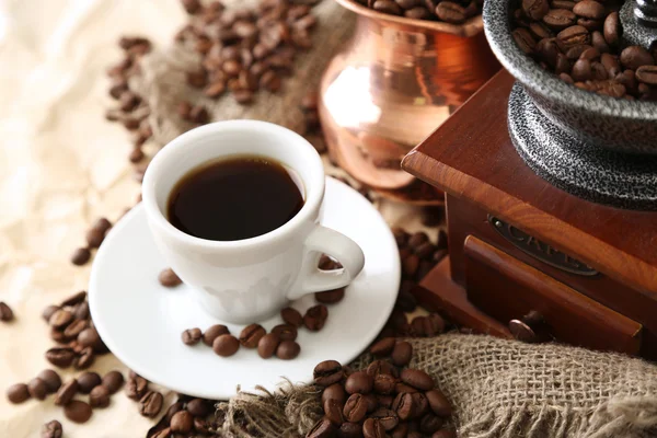 Kopp kaffe, potten och kvarnen på beige bakgrund — Stockfoto