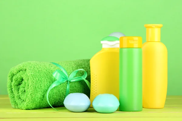 Baby cosmetica, handdoek en zeep op houten tafel, op groene achtergrond — Stockfoto