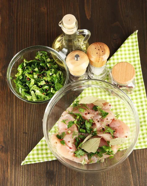 Kycklingkött i glasskål, örter och kryddor på träbord — Stockfoto