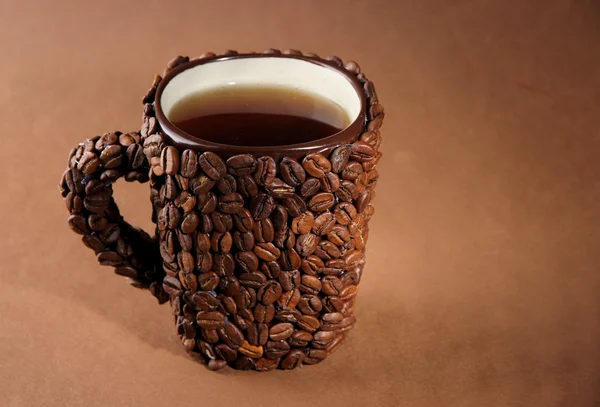 Xícara de grãos de café, em fundo marrom — Fotografia de Stock