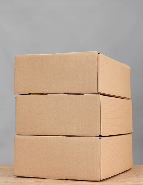 Cajas de paquetes sobre mesa de madera, sobre fondo gris — Foto de Stock