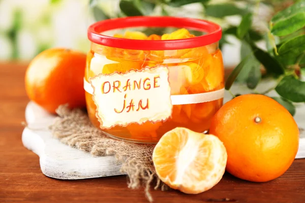 Orangenmarmelade mit Schale und Mandarinen, auf braunem Holztisch — Stockfoto