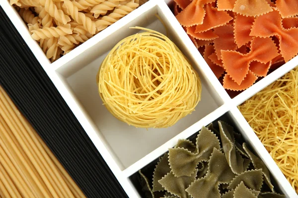 Diferentes tipos de pasta en secciones de caja de madera blanca de cerca —  Fotos de Stock