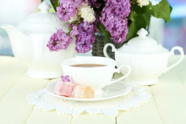 Composición con hermosas flores lila, servicio de té sobre mesa de madera sobre fondo brillante — Foto de Stock