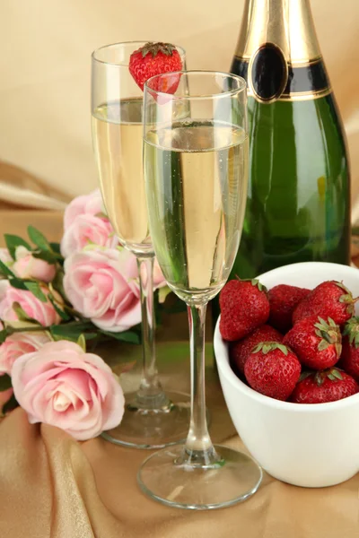 Романтический натюрморт с шампанским, клубничными и розовыми розами, на фоне цветной ткани — стоковое фото