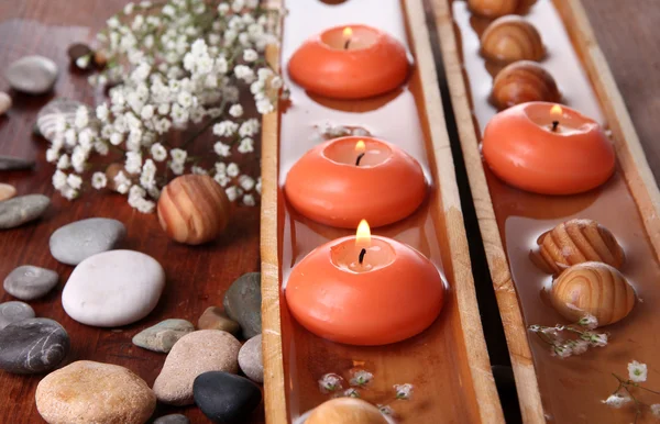 Beautiful candles in water on wooden table close-up