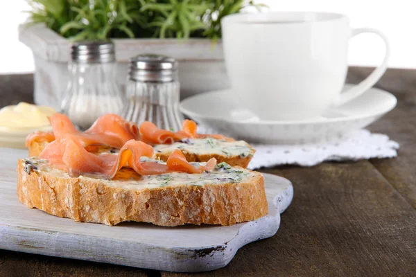 Vis broodjes en kopje thee op snijplank op houten tafel — Stockfoto