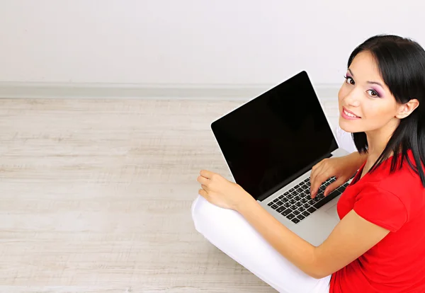 Bella giovane donna seduta con notebook in camera — Foto Stock